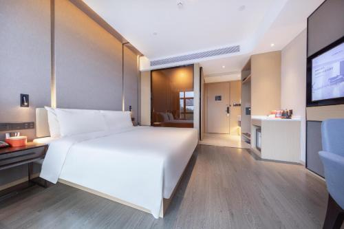a bedroom with a large white bed and a television at Atour Hotel Zhuhai Tangjiawan University Jinding Plaza in Zhuhai