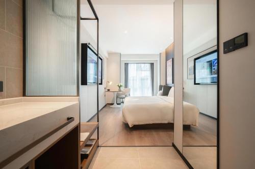 a bedroom with a bed and a bathroom with a mirror at Atour Hotel Chengdu East Station Greenland 468 Center in Chengdu
