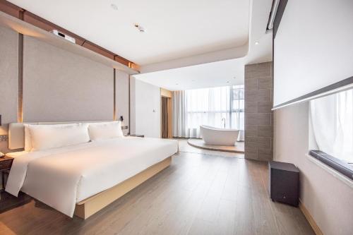 a bedroom with a large bed and a bath tub at Atour Hotel Shenzhen Fuhai International Convention and Exhibition Center in Bao'an