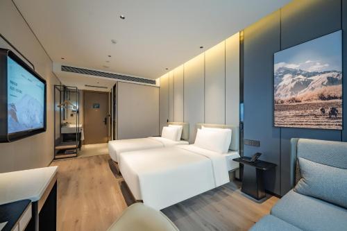 a room with two white beds and a flat screen tv at Atour Hotel Shanghai Huajing in Shanghai