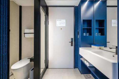 a bathroom with blue walls and a toilet and a sink at Atour Light Hotel Guangzhou Panyu Hanxi Changlong in Guangzhou