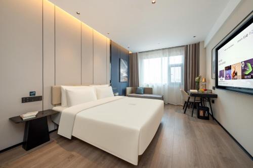 Schlafzimmer mit einem großen weißen Bett und einem Flachbild-TV in der Unterkunft Atour Hotel Nanchang Bayi Square Provincial Television Station in Nanchang