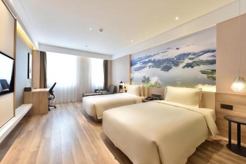 2 letti in una camera d'albergo con un dipinto sul muro di Atour Hotel Beijing Yizhuang Mobile Silicon Valley a Daxing