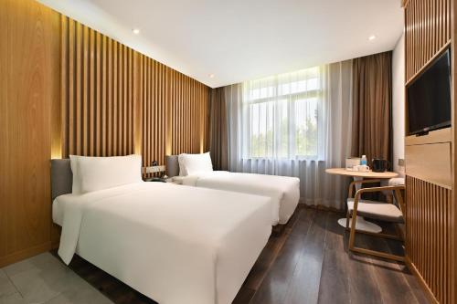 una camera d'albergo con due letti e una televisione di Atour X Hotel Beijing Sanlitun Agricultural Exhibition Hall a Pechino