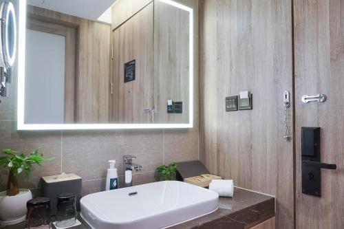 Atour Hotel Harbin Songbei Ice and Snow World في هاربين: حمام مع حوض أبيض ومرآة