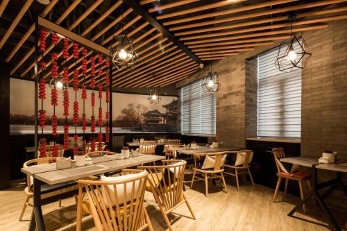 a dining room with tables and chairs and windows at Atour Hotel Beijing Yansha Sanyuan Bridge in Beijing