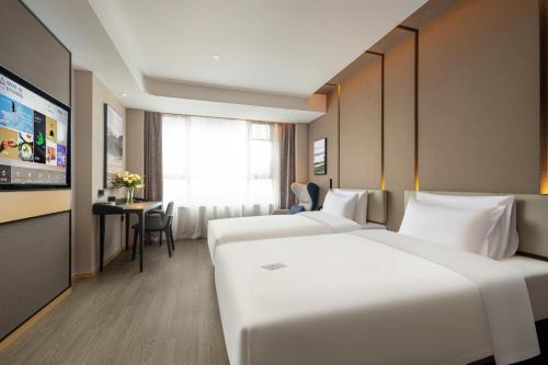 LinhaiにあるAtour Hotel Taizhou Linhai Taizhou Universityのベッド2台とテーブルが備わるホテルルームです。