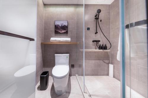 La petite salle de bains est pourvue d'une douche et de toilettes. dans l'établissement Atour Hotel Qingdao Laoshan Shilaoren Beach, à Qingdao