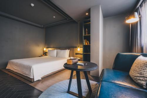a bedroom with a bed and a table and a couch at The Drama in Shanghai