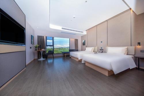 a hotel room with two beds and a flat screen tv at Atour Hotel Zhuhai High Tech Zone University Town Government Affairs Center in Zhuhai