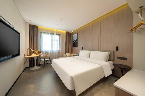 a hotel room with a large white bed and a table at Atour Hotel Shanghai Wujiaochang West Yingao Road Station in Shanghai