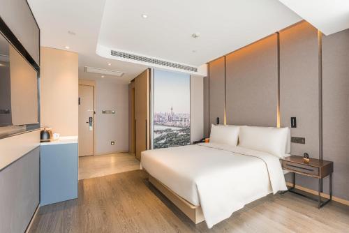 a bedroom with a white bed and a large window at Atour Hotel Tianjin Binhai High Speed Railway Station in Binhai