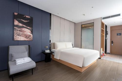 a bedroom with a large white bed and a chair at Atour X Hotel Zhuhai Gongbei Port High Speed Railway Station in Zhuhai