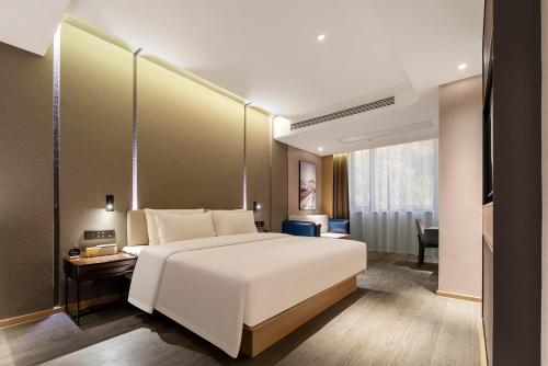 a bedroom with a large white bed and a desk at Atour Hotel Shaoxing Heqiao in Shaoxing