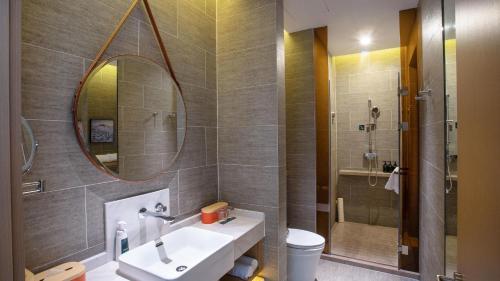 La salle de bains est pourvue d'un lavabo et d'un miroir. dans l'établissement Atour Hotel Lijiang Old Town Waterwheel, à Lijiang