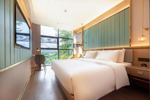 una camera da letto con un grande letto bianco e una finestra di Atour Light Hotel Shenzhen Nanshan Shenzhen Bay a Shenzhen