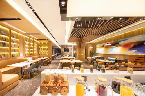 a restaurant with tables and chairs and a painting on the wall at Atour Hotel Kunming Cuihu in Kunming