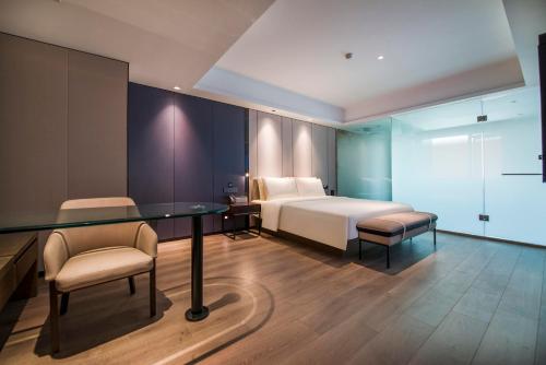 1 dormitorio con 1 cama, mesa y sillas en Atour X Hotel Dongguan Chang'an Wanda, en Dongguan