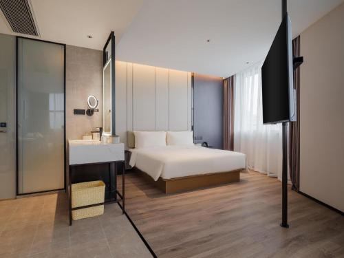 a hotel room with a bed and a television at Atour Hotel Xiamen North Station Jiageng Stadium in Xiamen