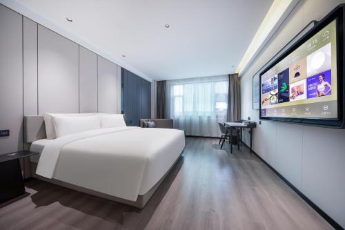a hotel room with a white bed and a flat screen tv at Atour X Hotel Guangzhou Baiyun International Airport Renhe Station in Guangzhou
