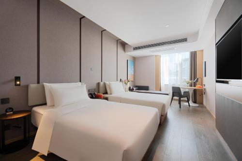 a hotel room with three beds and a flat screen tv at Atour Hotel Lijiang Old Town Waterwheel in Lijiang