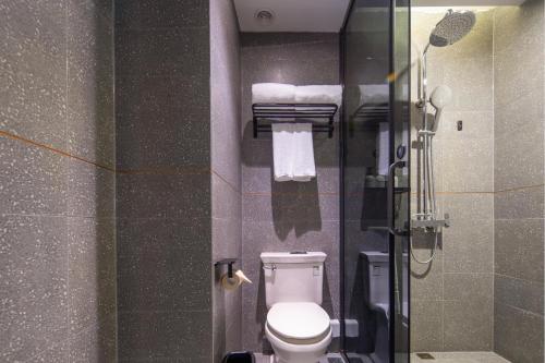 ein Badezimmer mit einem WC und einer Glasduschkabine in der Unterkunft Atour X Hotel Shanghai Jinshan Wanda Plaza City Beach in Jinshan