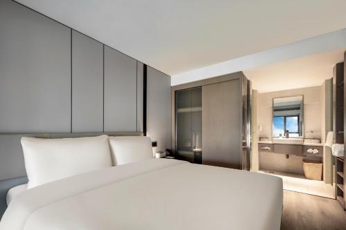 a bedroom with a large white bed and a bathroom at Atour X Hotel Xiamen SM Plaza District Government in Xiamen