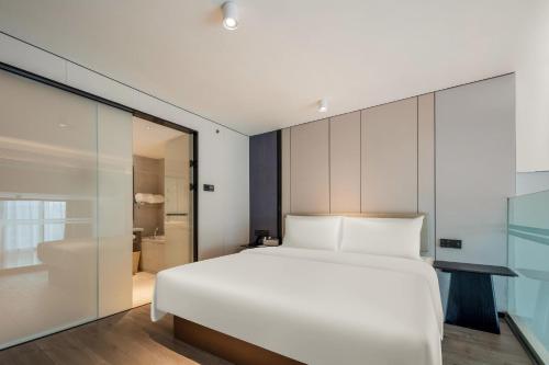 a bedroom with a white bed and a glass wall at Atour X Hotel Xiamen SM Plaza District Government in Xiamen