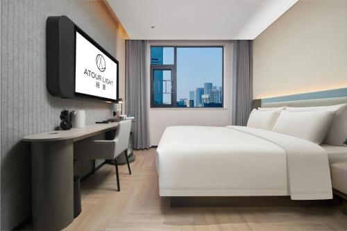 a hotel room with a bed and a desk and a tv at Atour Light Hotel Changsha IFC Huangxing Road Pedestrian Street in Changsha