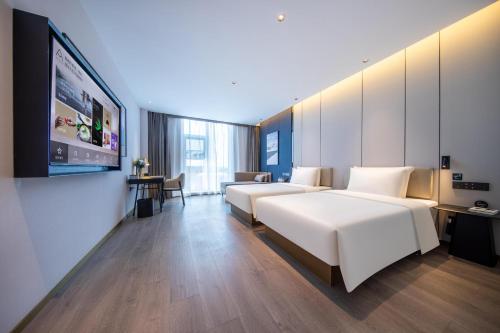 a hotel room with two beds and a flat screen tv at Atour Hotel Beijing Capital Airport New International Exhibition Center in Beijing