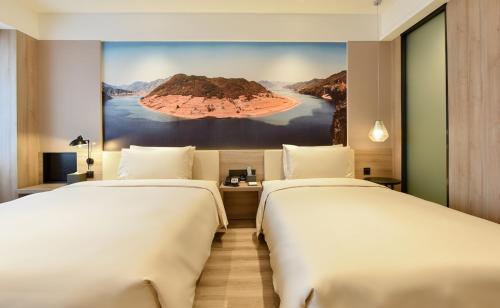 2 camas en una habitación de hotel con un cuadro en la pared en Atour Hotel Shenyang Youth Street Golden Gallery, en Shenyang
