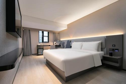 a bedroom with a large white bed and a desk at Atour Light Hotel Wuhan Jiangtan Jianghan Road Pedestrian Street in Wuhan