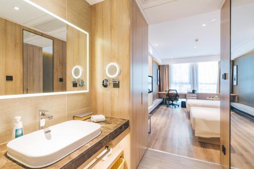 een badkamer met een wastafel en een spiegel bij Atour Hotel Hangzhou Qianjiang New Town in Hangzhou