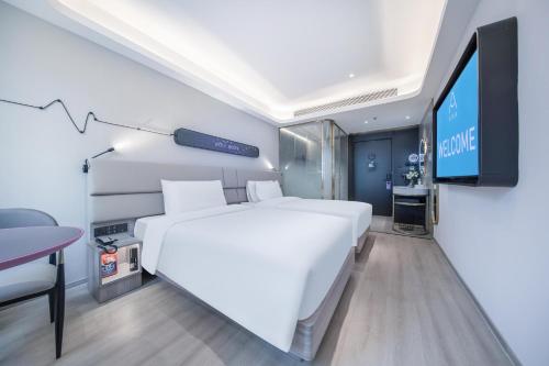 a bedroom with a large white bed and a flat screen tv at Atour Light Hotel Shenzhen Nanshan Nanyouxi Station in Shenzhen