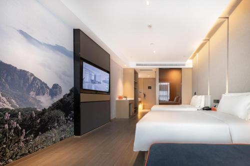 a hotel room with a large bed and a flat screen tv at Atour Hotel Taian Taishan Internation Convention and Exhibition Center in Tai'an