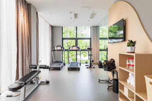 a gym with treadmills and ellipticals in a room with windows at Atour Hotel Xiamen Xiagu Cruise Center in Xiamen