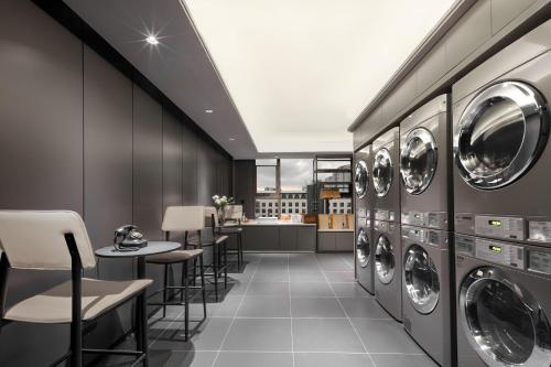 a laundry room with washing machines and tables and chairs at Atour Hotel Quanzhou Jinjiang Sunshine Plaza in Jinjiang