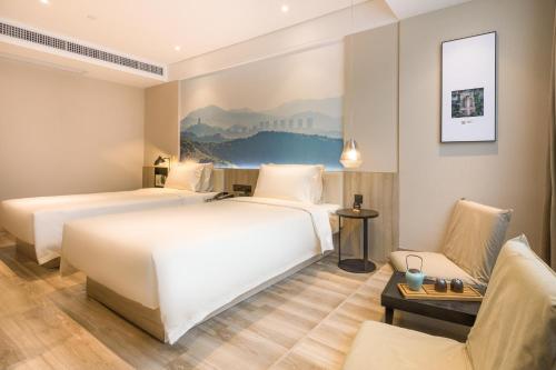 a hotel room with two beds and a couch at Atour Hotel Guangzhou Huadu Square in Huadu