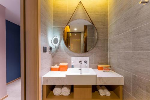 ein Bad mit einem Waschbecken und einem Spiegel in der Unterkunft Atour Hotel Chongqing Tiandi NetEase Cloud Music in Chongqing