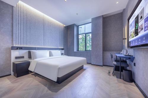 a bedroom with a large white bed and a desk at Atour Light Hotel Fuzhou Sanfang Qixiang in Fuzhou