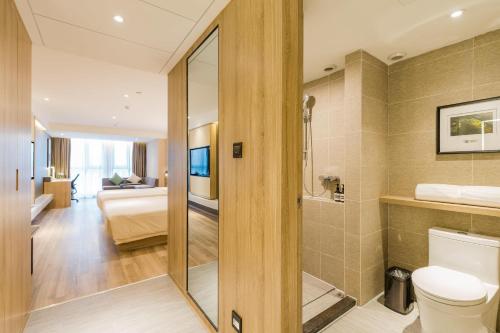 a bathroom with a toilet and a bedroom at Atour Hotel Hangzhou West Lake Cultural Plaza Shangtang Road in Hangzhou