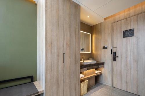 La salle de bains est pourvue d'un lavabo et d'un mur en bois. dans l'établissement Atour Hotel Shanghai Minhang Industrial Park, à Shanghai