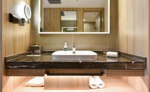 a bathroom with a sink and a mirror at Atour Hotel Shenyang Youth Street Golden Gallery in Shenyang