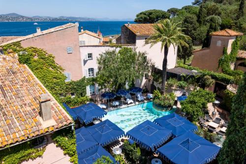 サントロペにあるVillas by Le Yaca Saint-Tropezのリゾートの空中を望む客室で、プールと青い傘が備わります。