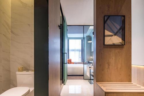 a bathroom with a toilet and a room with a bed at Atour S Hotel Shanghai Hongqiao Center Aegean in Shanghai