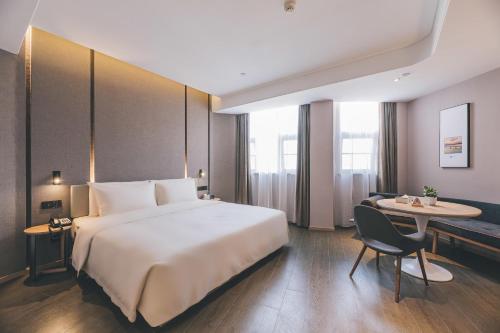 a hotel room with a large bed and a table at Atour Hotel Chaozhou Ancient Town People's Square in Chaozhou