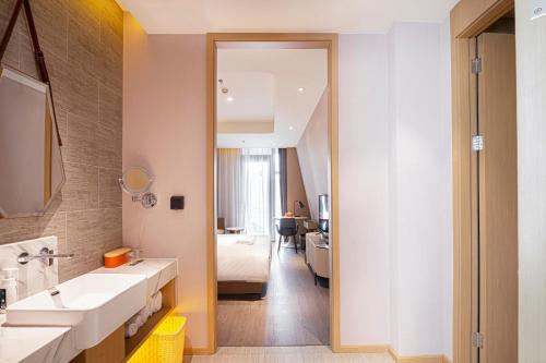 łazienka z umywalką, łóżkiem i lustrem w obiekcie Atour Hotel Tianjin Eye w mieście Tiencin
