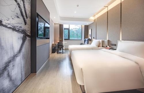 昆明市にあるAtour Hotel Kunming Cuihuのベッド2台とテーブルが備わるホテルルームです。