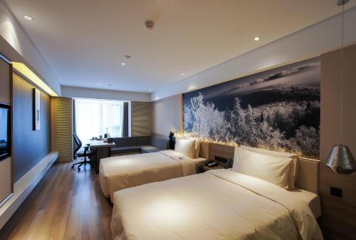 a hotel room with two beds and a desk at Atour Hotel Harbin Haxi High Speed Railway Station in Harbin