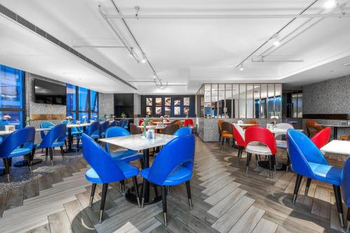 Atour Hotel Chengdu Jiuyanqiao NetEase Selected في تشنغدو: مطعم به كراسي وطاولات زرقاء وحمراء